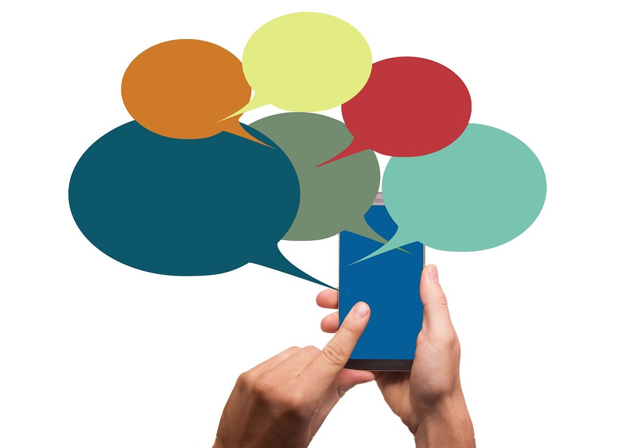 スマホをタッチする人の手と、そこから出ている様々な色の会話吹き出しイラスト